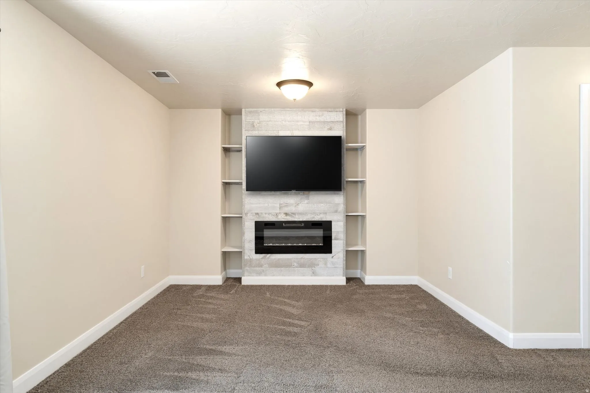 Built-in media center with shelving, electric fireplace, and mounted television