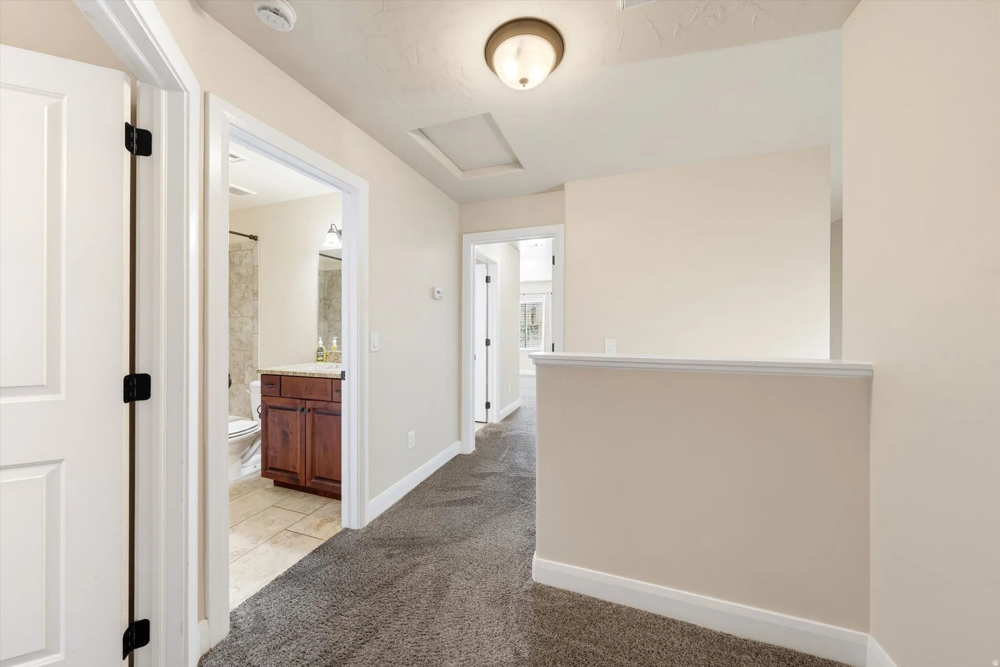 Hallway with gray textured carpet, recessed lighting, and white trim