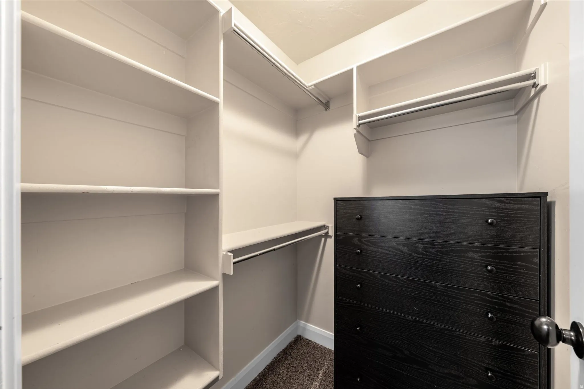 Built-in shelving, integrated hanging rods, and a dark wood-finish dresser with black hardware