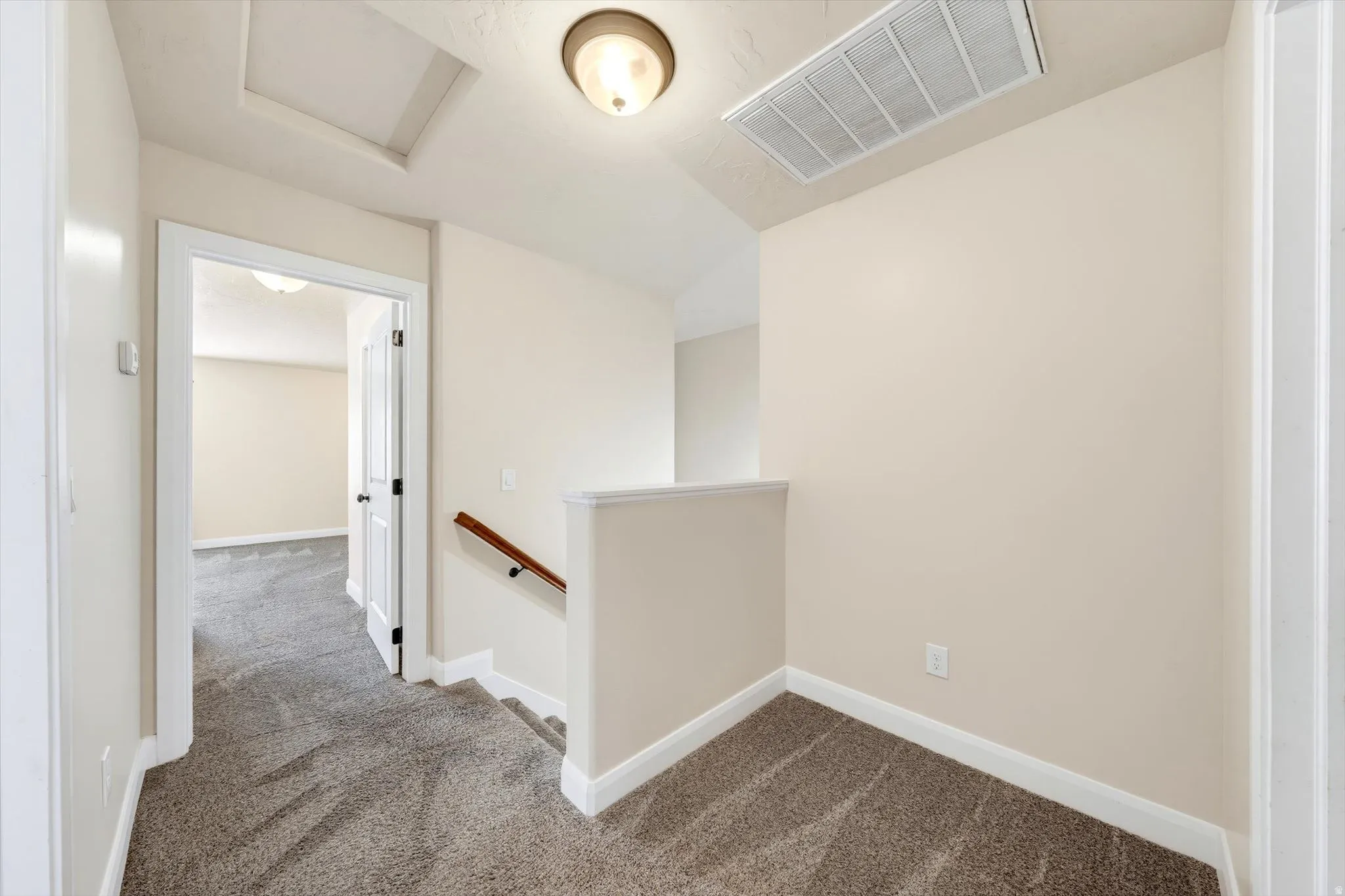 Neutral wall paint, plush carpet flooring, white trim, wood handrail, and flush mount lighting