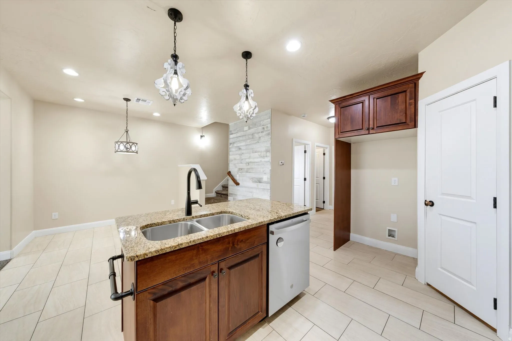 Kitchen island with a double basin sink, granite-style countertop, and wood-finish cabinetry