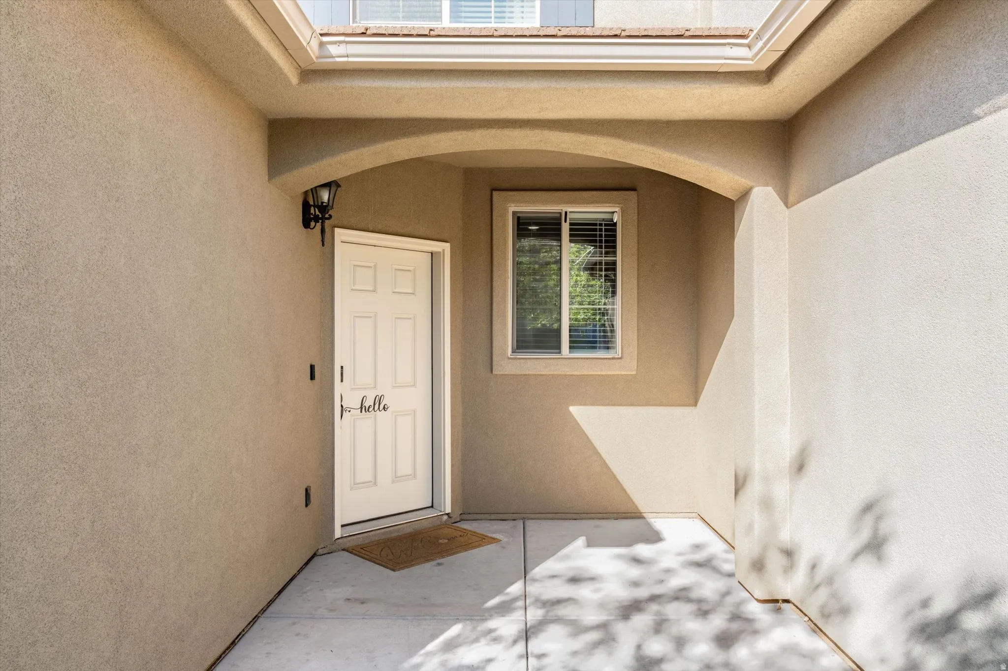 Covered entry with concrete flooring, an arched alcove, and a mounted exterior light fixture