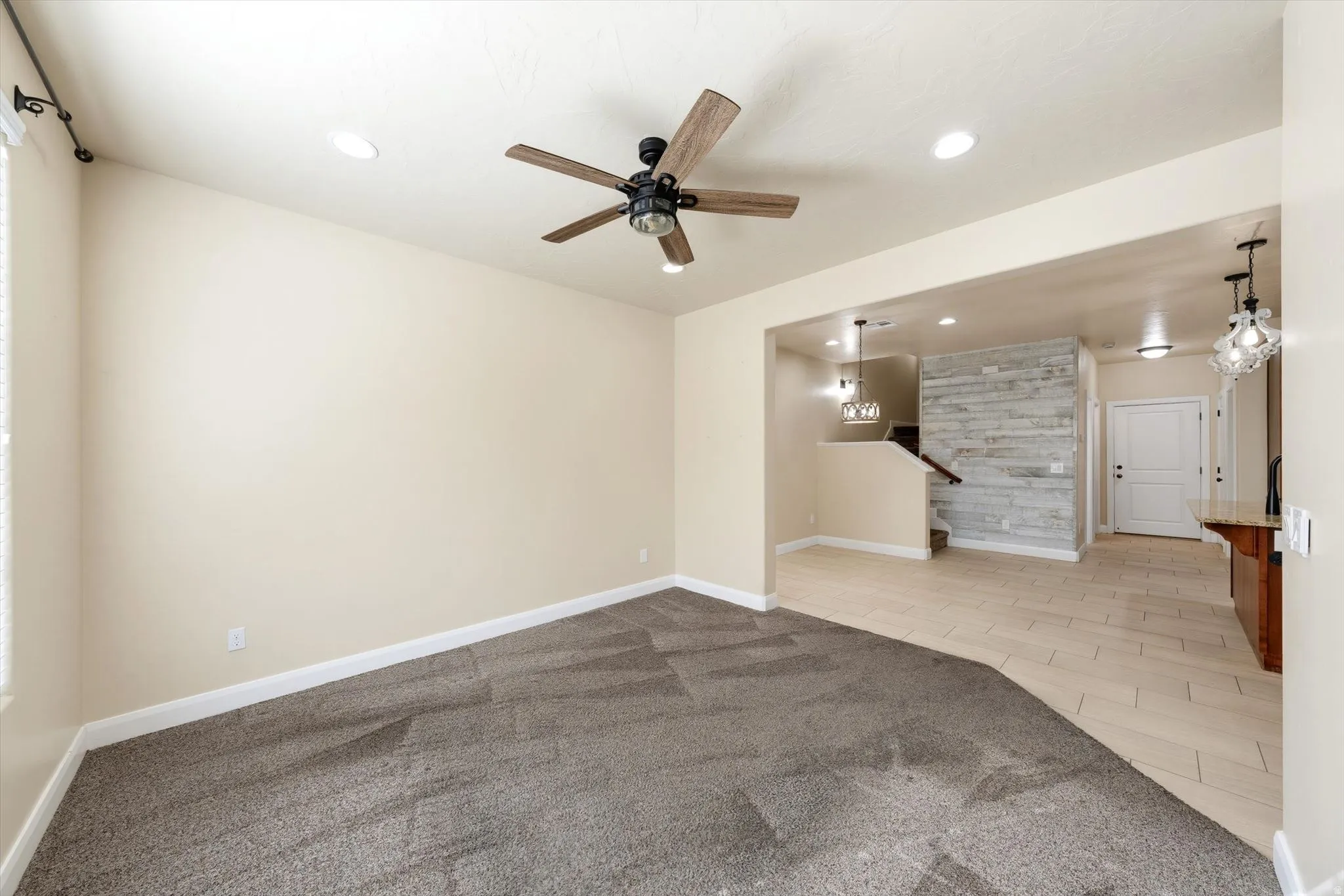 Recessed ceiling lighting, ceiling fan, wood-look plank wall accent, and tile flooring
