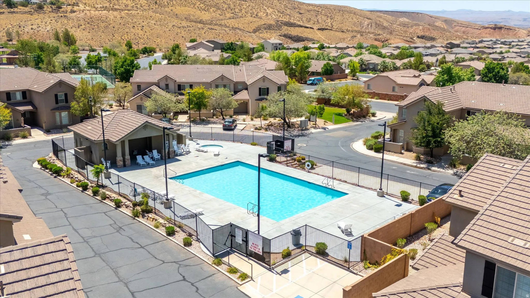 Community swimming pool with surrounding concrete decking, fenced perimeter, and adjacent spa