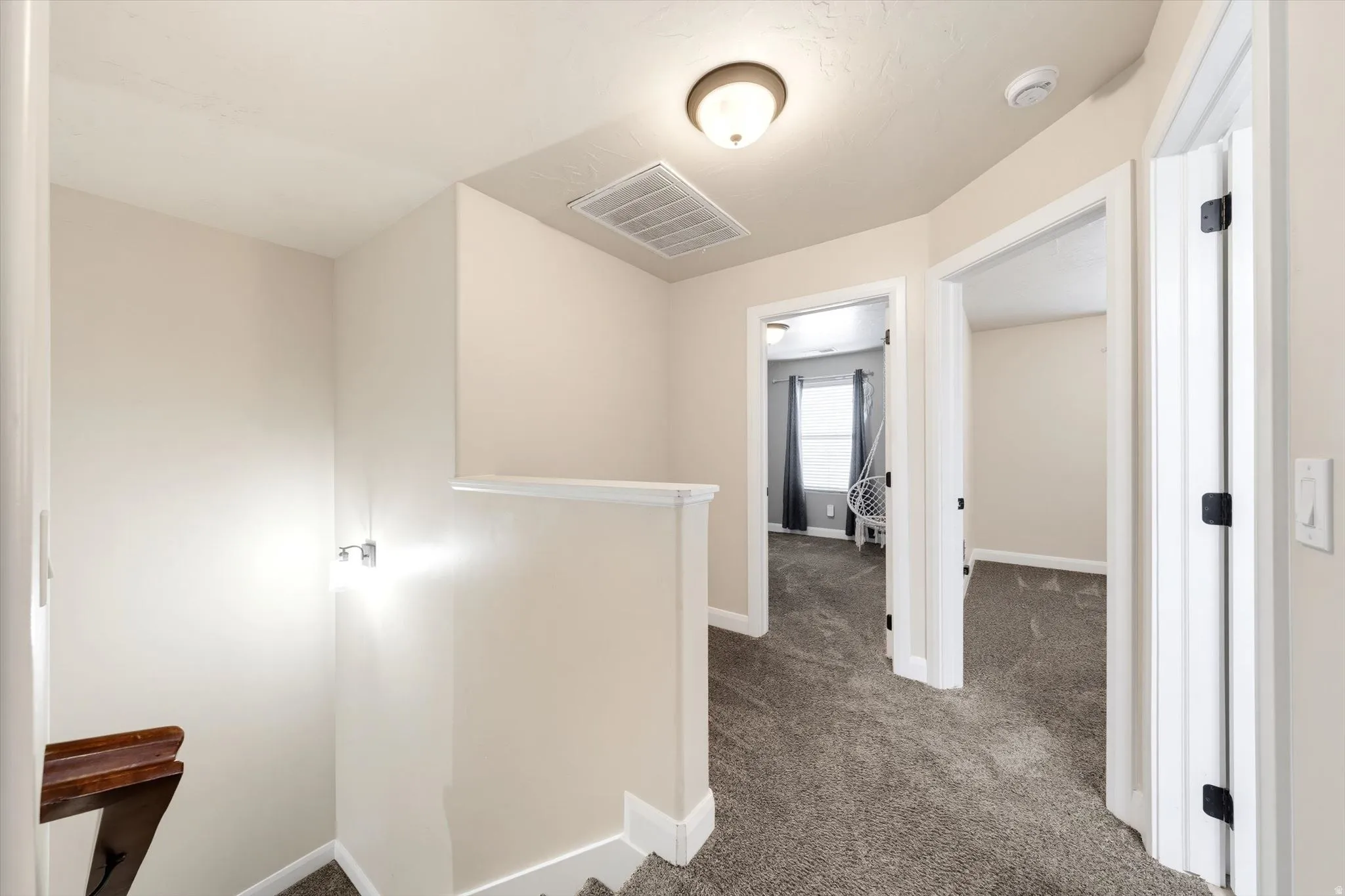 Neutral wall color with plush gray carpeting, white trim, and a semi-flush mount ceiling light