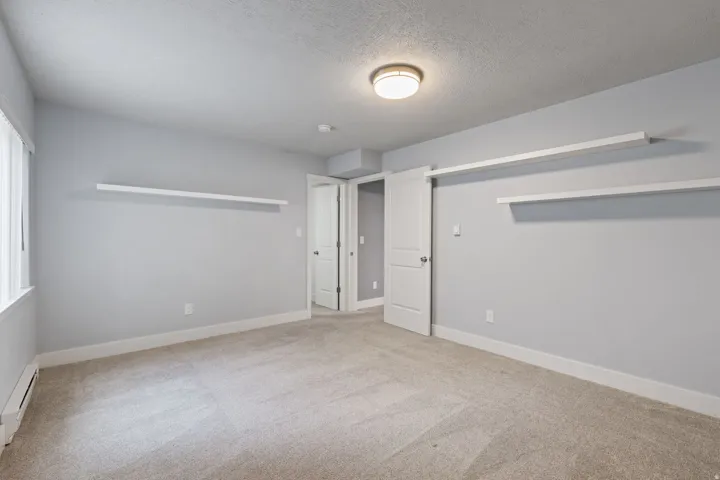Carpeted flooring, two floating shelves, recessed ceiling light, white trim, and a window