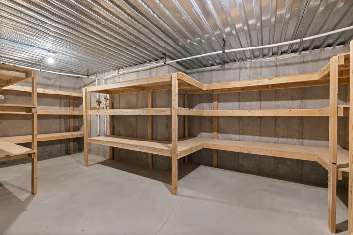 Concrete flooring with extensive built-in wooden shelving, concrete block walls, and exposed metal ceiling