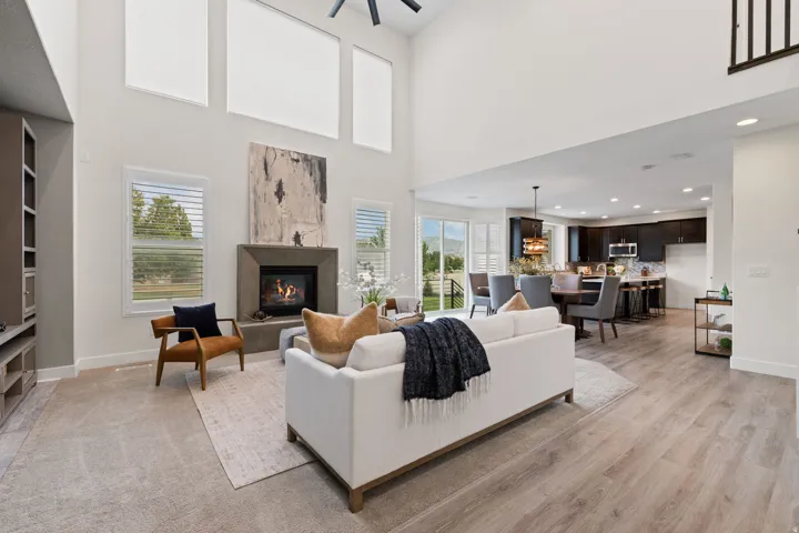 Open-concept living area with a two-story ceiling, a fireplace with a stone surround, and wood-finish flooring