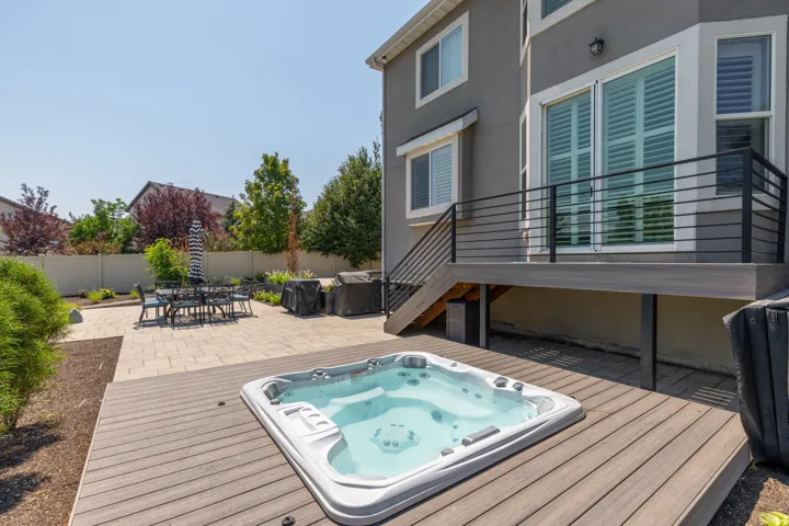 Expansive outdoor space featuring a built-in spa, composite deck, and paver patio