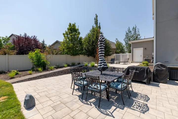 Expansive paver patio with a private perimeter fence and landscaped planting beds
