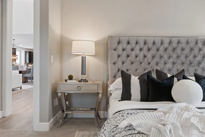 Tufted headboard, recessed lighting, neutral wall color, wood-finish flooring, and white trim