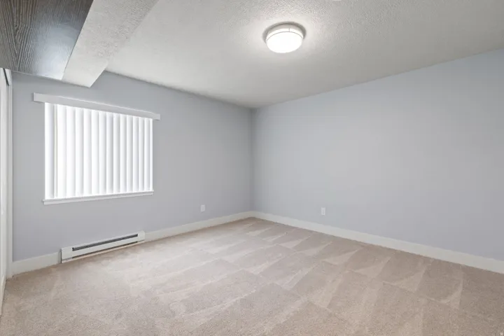 Recessed lighting, light gray wall finish, window with vertical blinds, baseboard heating unit, and neutral-toned carpet flooring