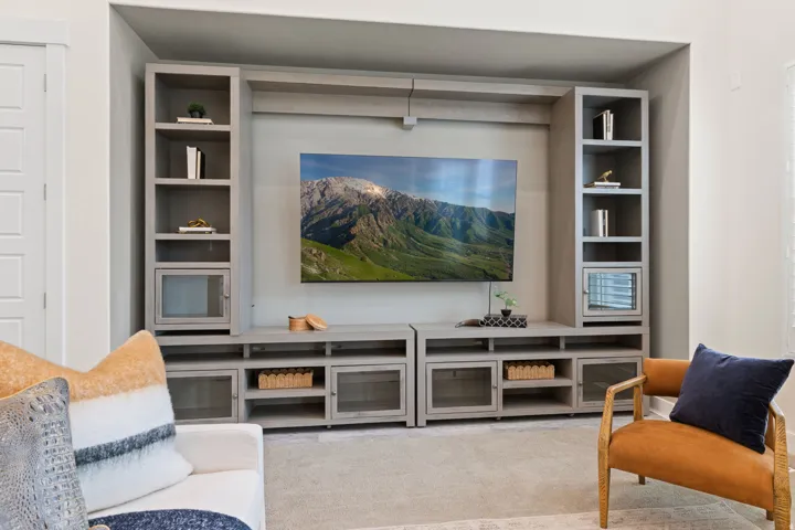Built-in media center with open shelving, glass-front cabinets, and integrated television alcove