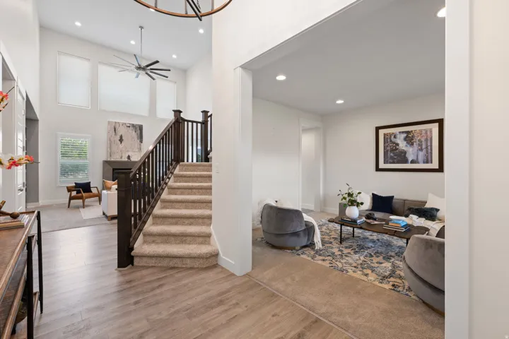 Two-story foyer with wood-finish flooring, a carpeted staircase with wood banisters, and a living area featuring a fireplace