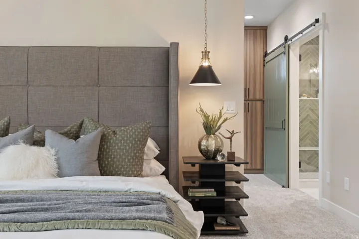 Upholstered headboard, overhead pendant light fixture, built-in cabinetry, and barn door entry