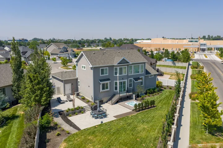 Expansive backyard featuring a hot tub, multiple patio areas, and a detached garage structure
