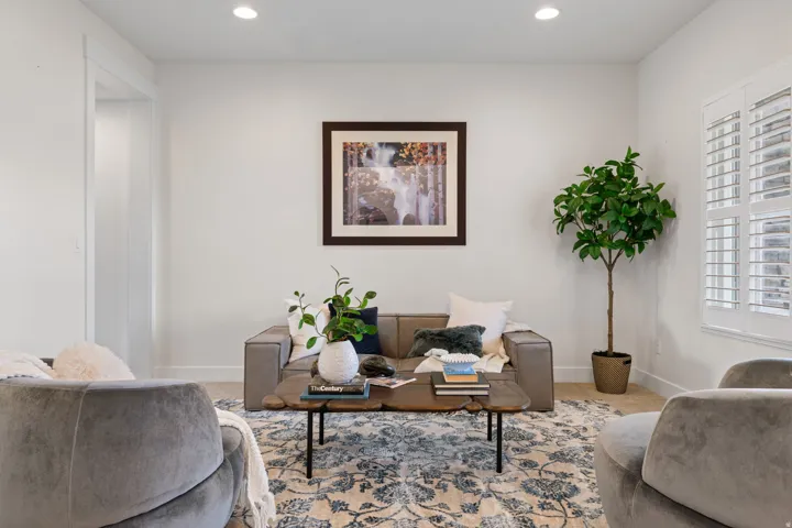 Bright and airy living room showcasing recessed ceiling lighting, neutral wall finishes, and plush upholstered seating areas