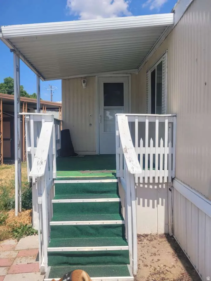 Covered entrance with white railings and green step carpeting