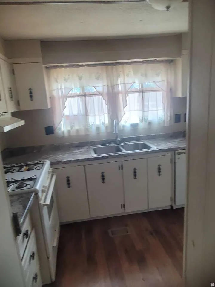 Kitchen featuring a double basin sink, white cabinetry, a built-in oven with cooktop, and wood-finish flooring