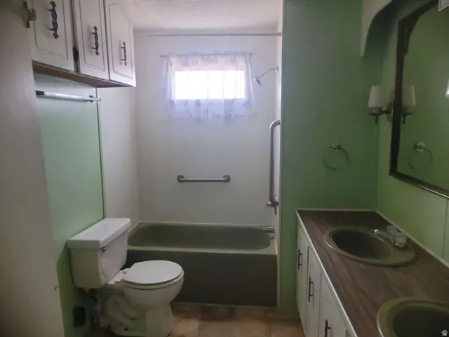 Bathroom featuring a dual vanity with integrated sinks, a wood-finish countertop, and wall-mounted sconces