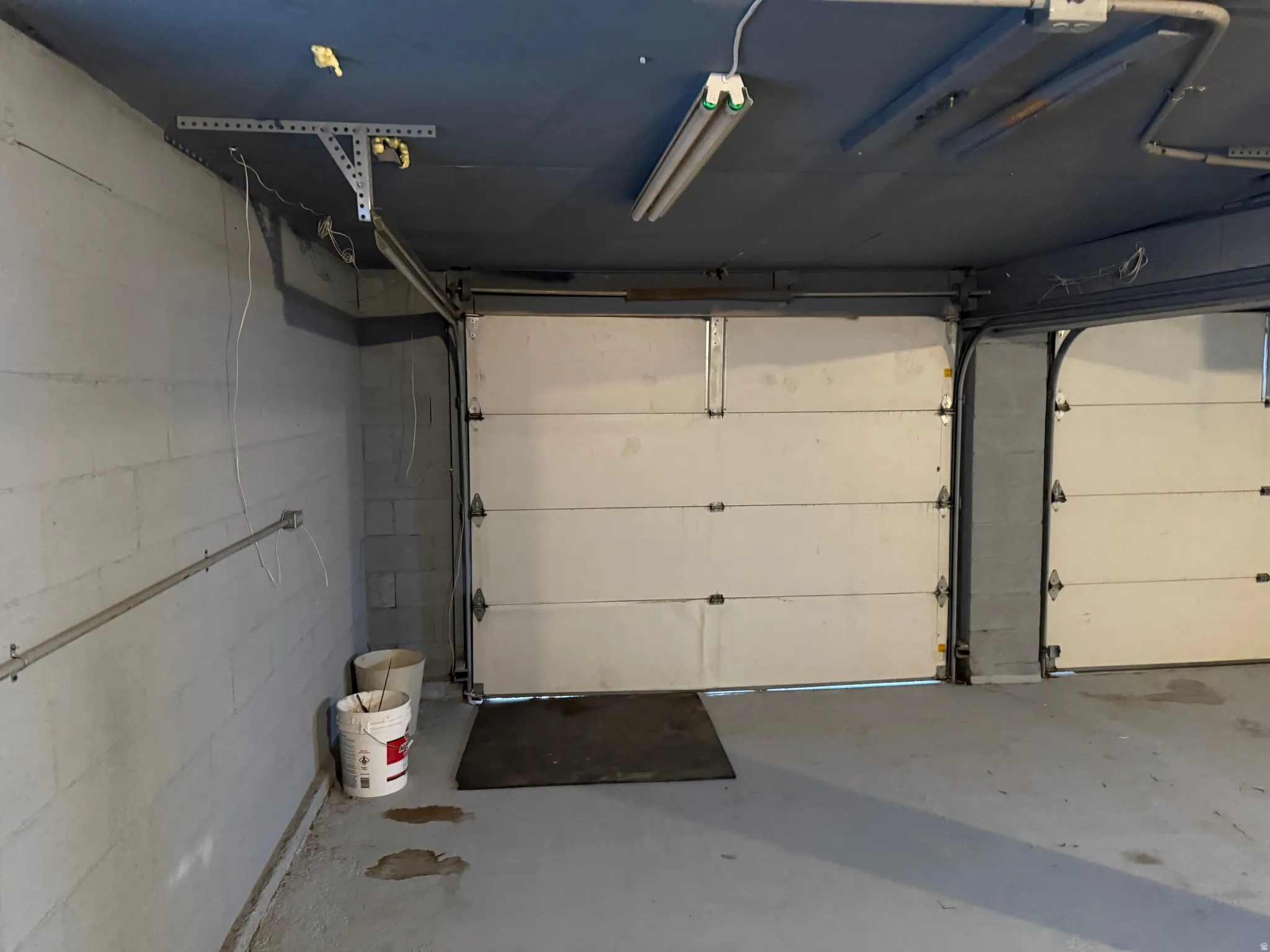 Concrete block walls with overhead fluorescent lighting and two garage doors