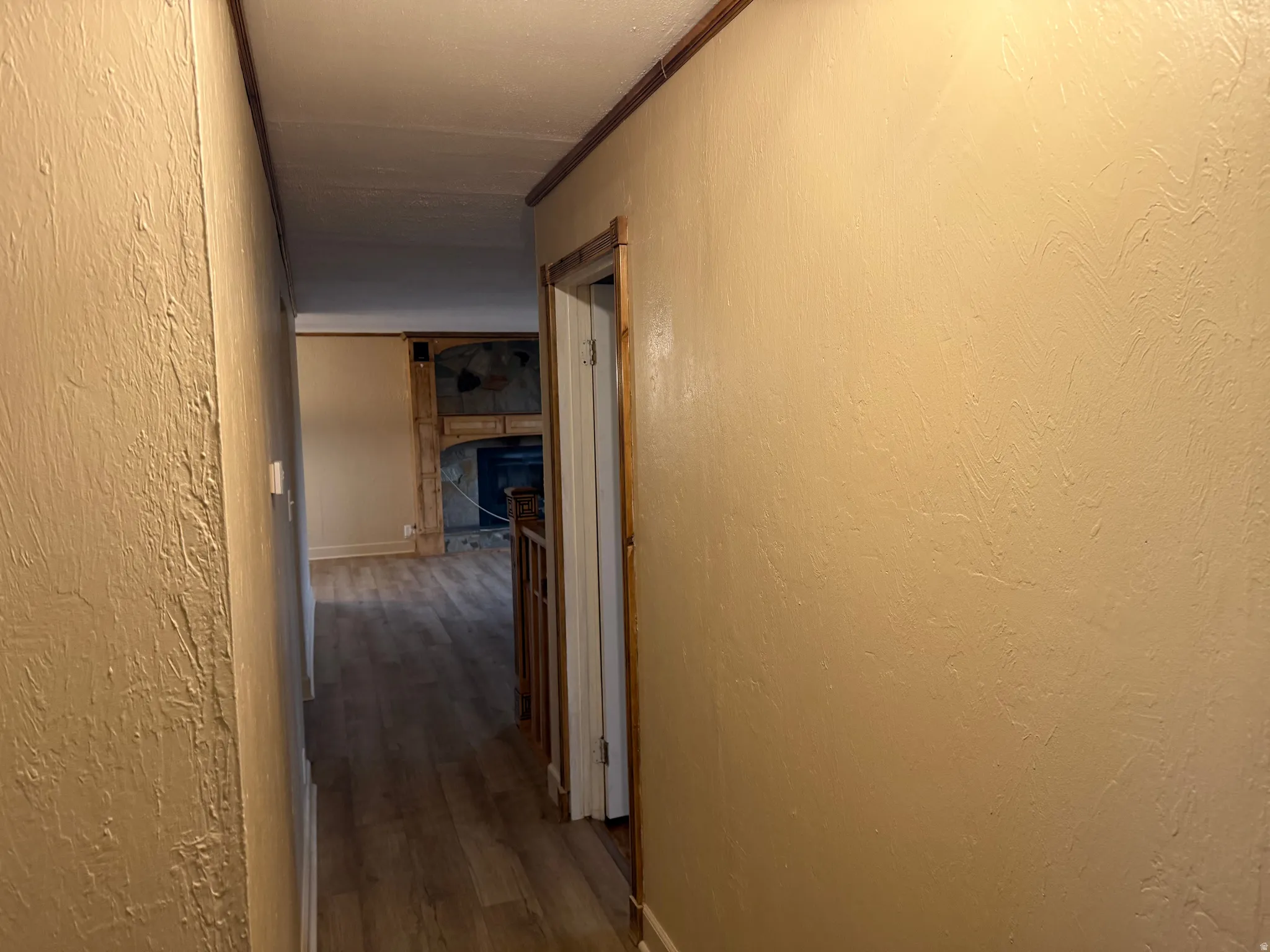 Wood-finish flooring throughout, detailed wood trim, and a prominent stone fireplace surround