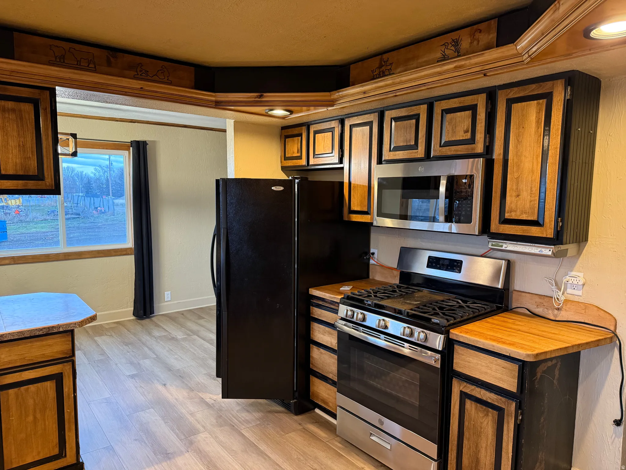 Kitchen featuring wood-finish cabinetry, stainless steel range, and stainless steel microwave