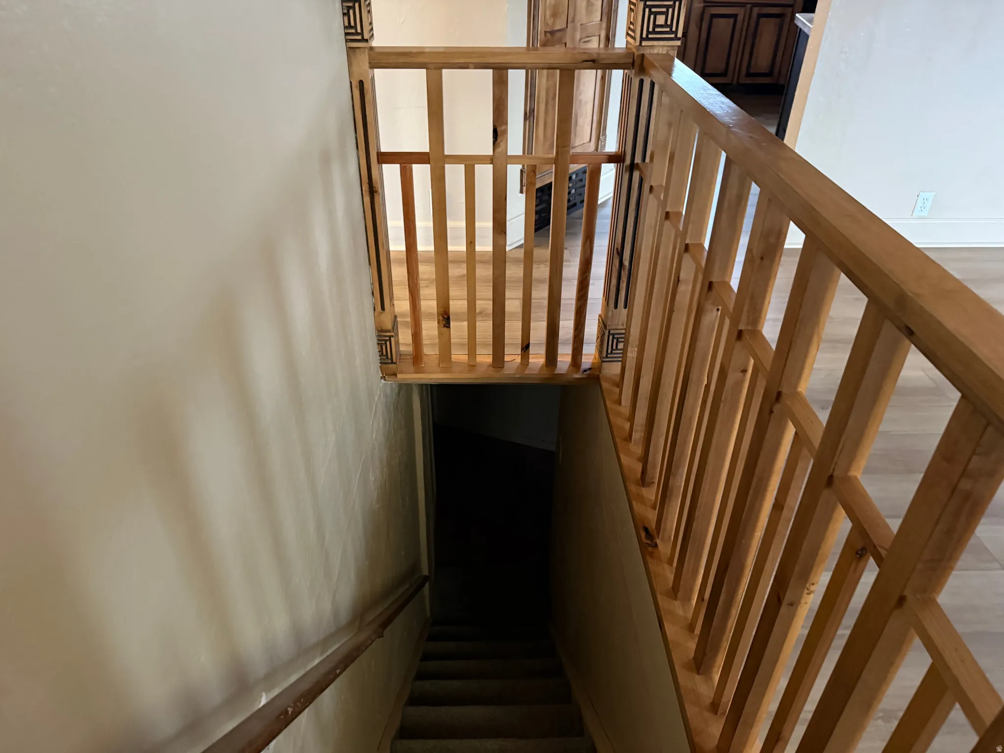 Light wood staircase railing with decorative newel posts, complementing wood-finish flooring