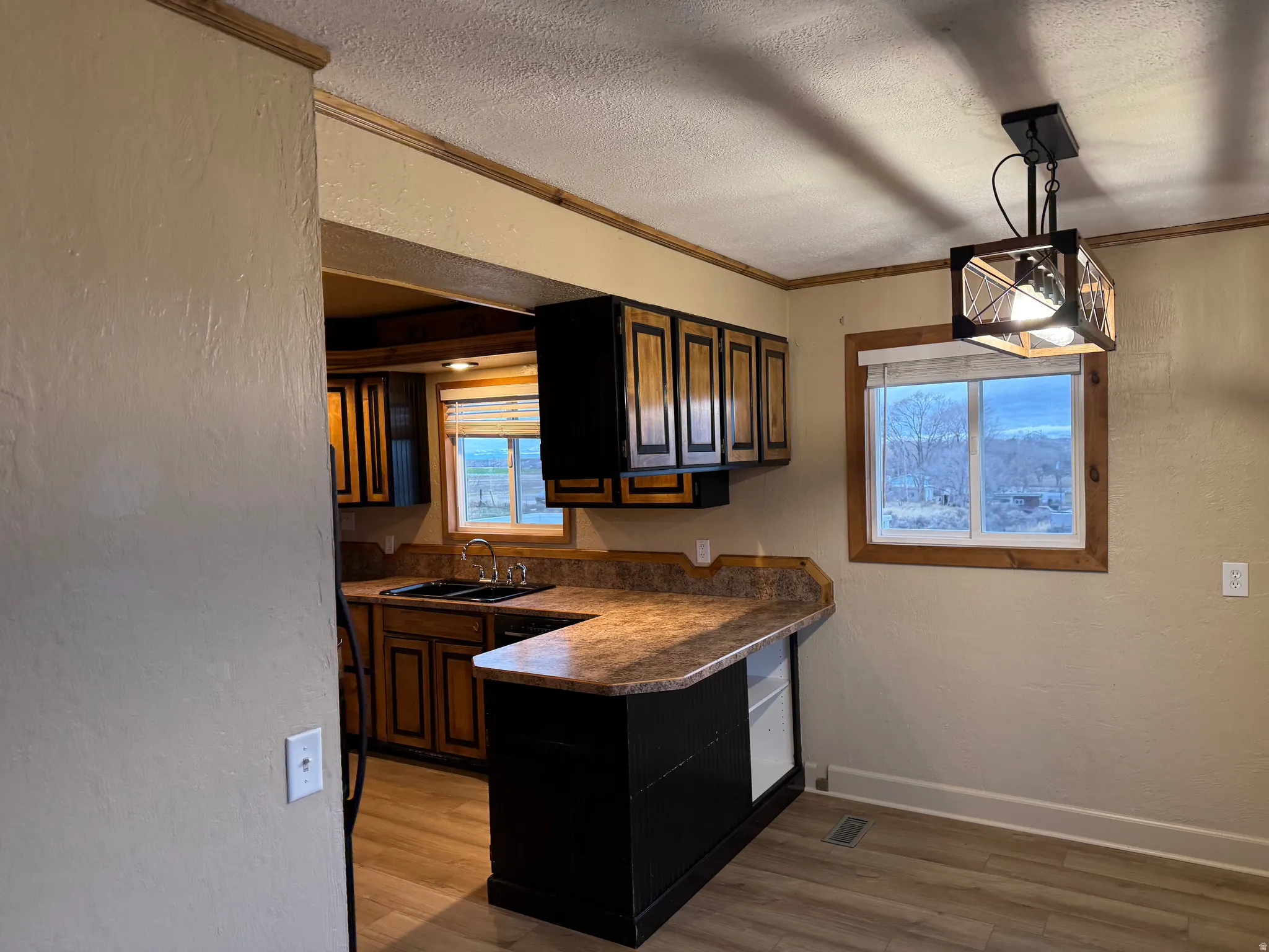 Wood-finish flooring, wood-framed window, pendant light fixture, wood-detailed cabinetry, and a built-in breakfast bar