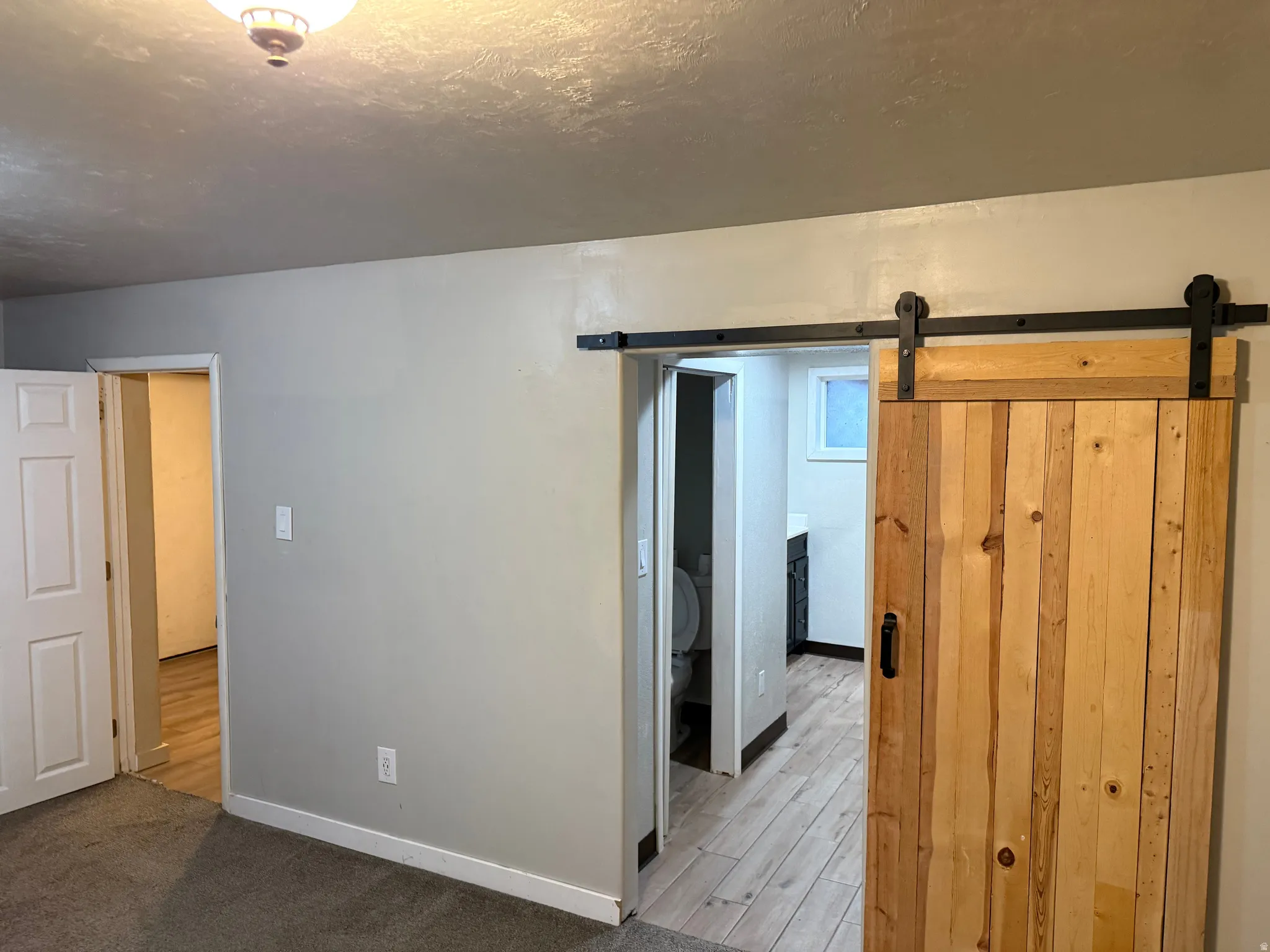 Rustic wood barn door with black hardware, leading to a space with wood-finish flooring