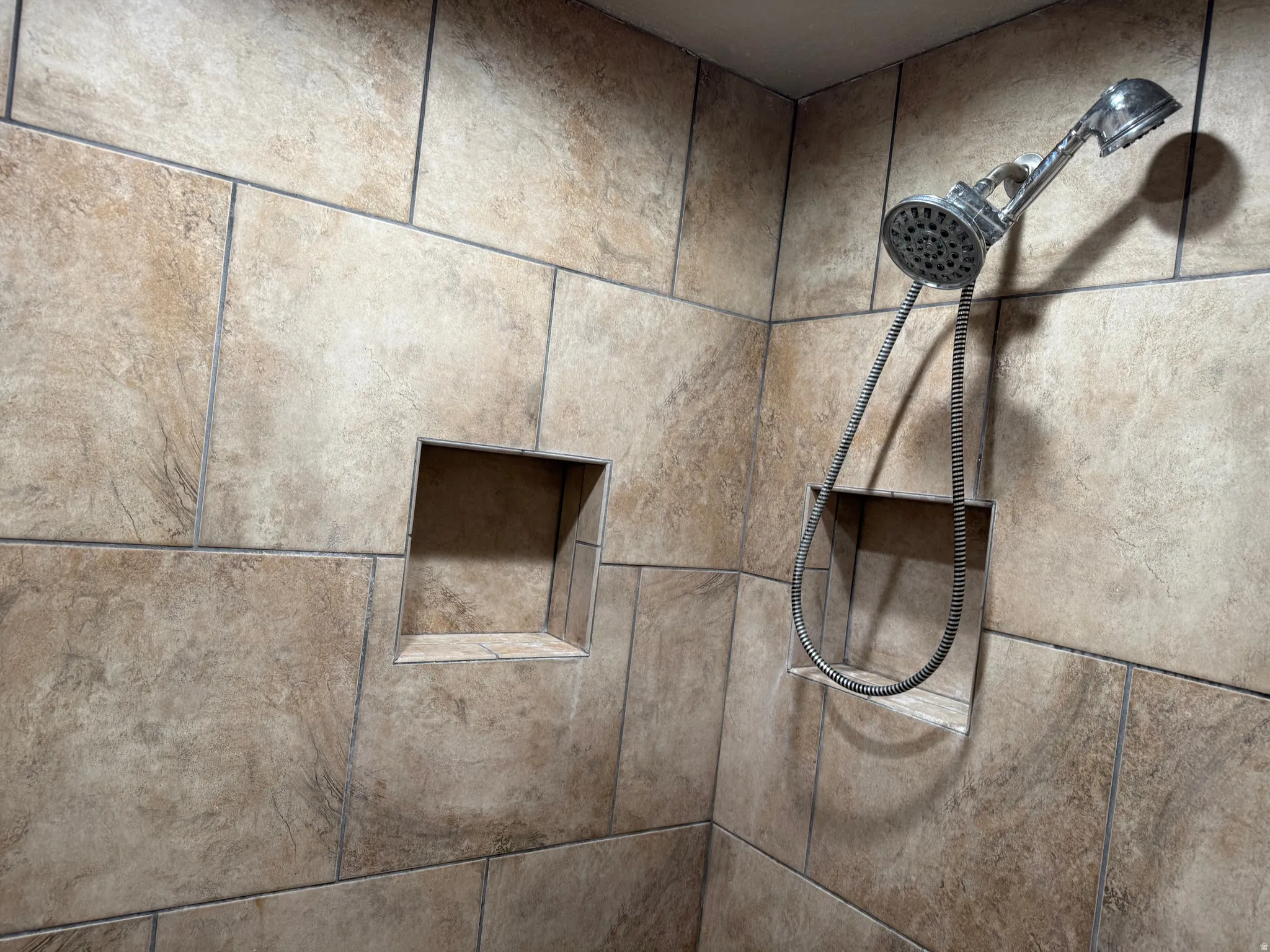 Tiled shower surround with two recessed niches and a handheld showerhead
