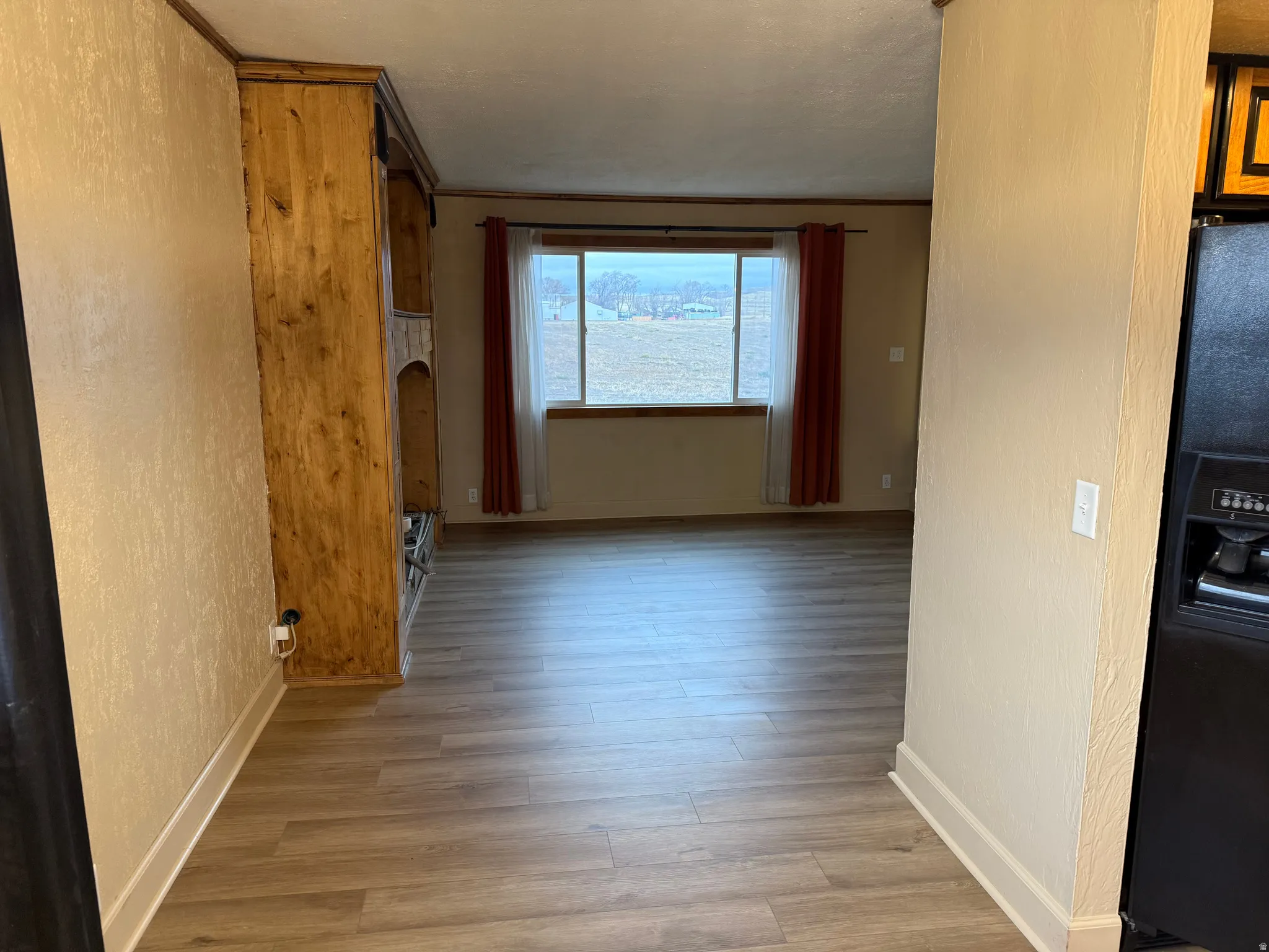 Wood-finish flooring throughout, built-in wooden cabinetry, and a large window