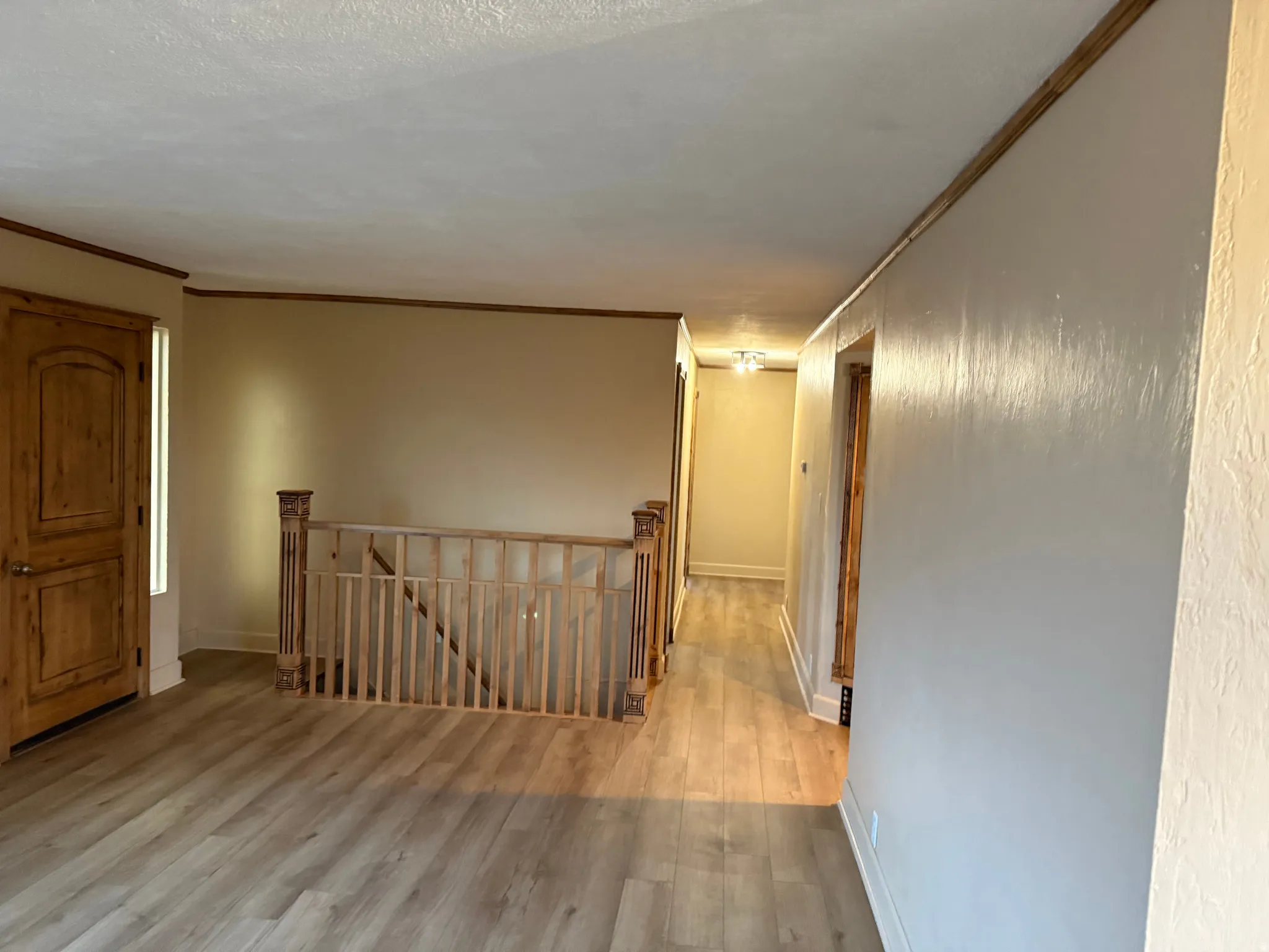 Wood-finish flooring, natural wood door, wood staircase railing, and wood trim accents throughout