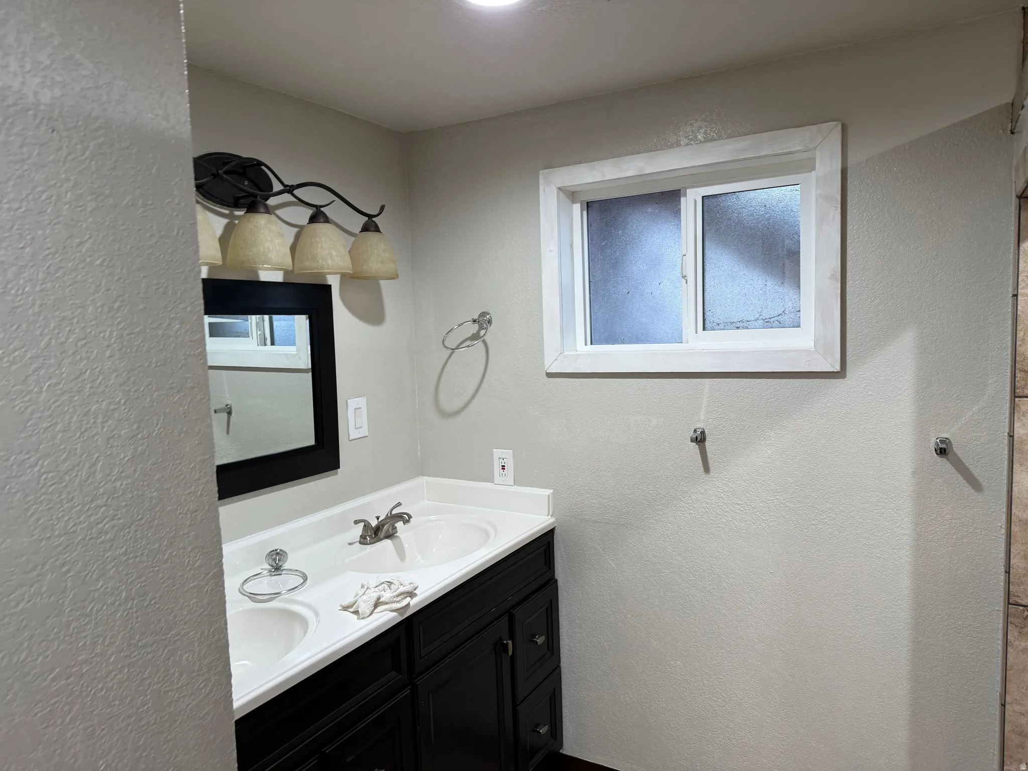 Dual vanity with integrated sinks, dark wood-finish cabinetry, and a framed mirror