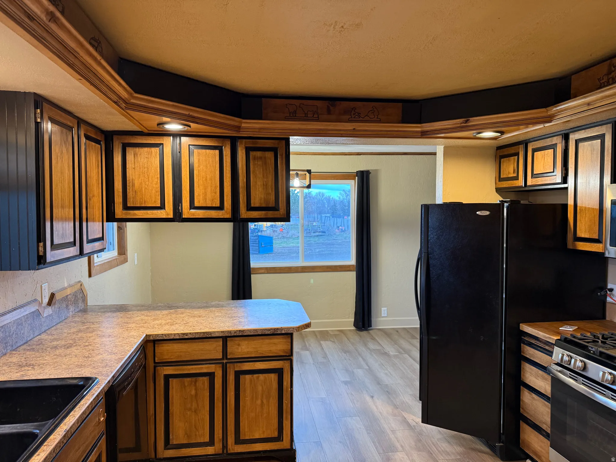Kitchen featuring wood-finish cabinetry, black appliances, laminate countertops, and recessed lighting