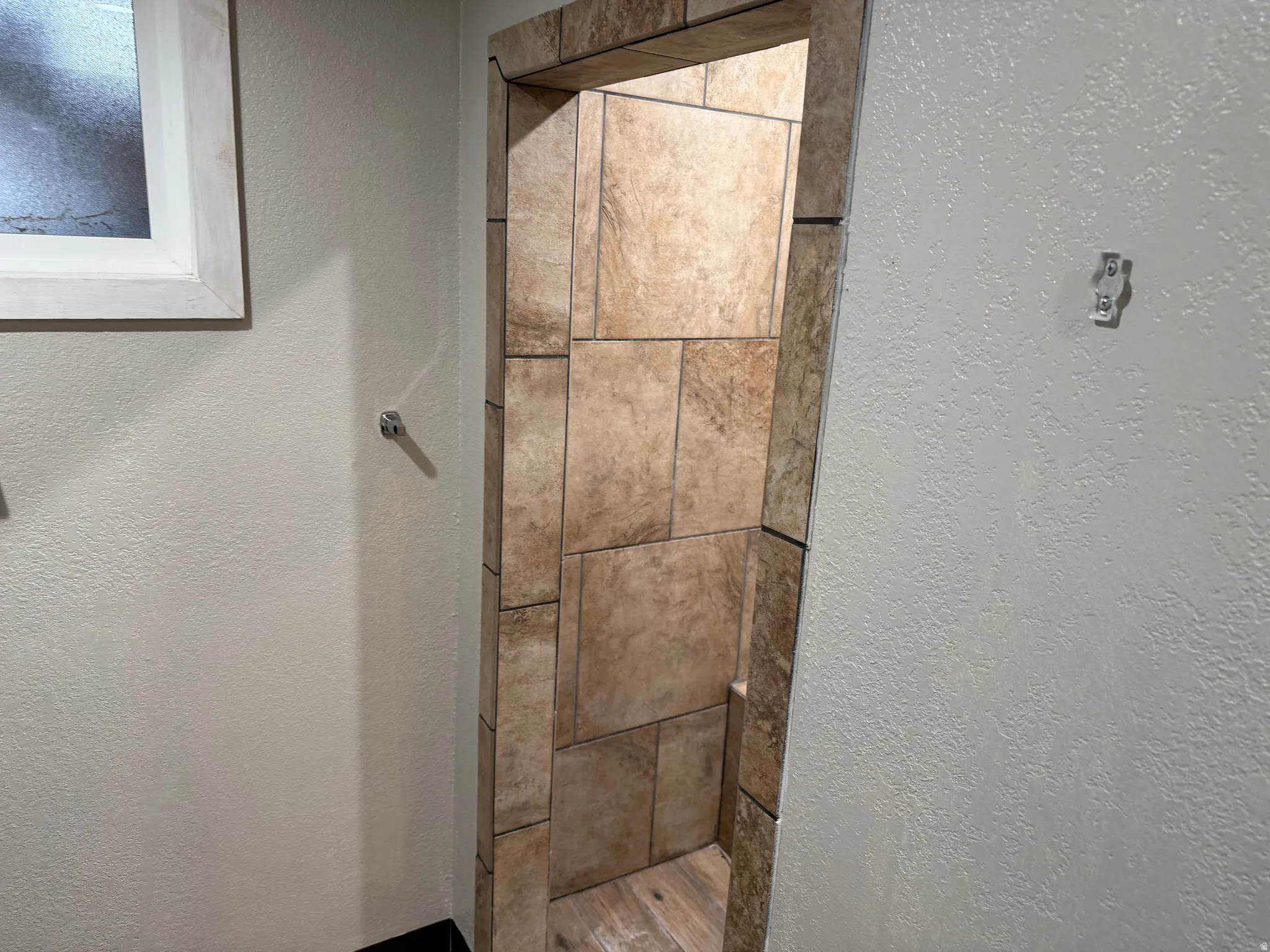Tiled shower enclosure featuring varied tile sizes and an integrated bench