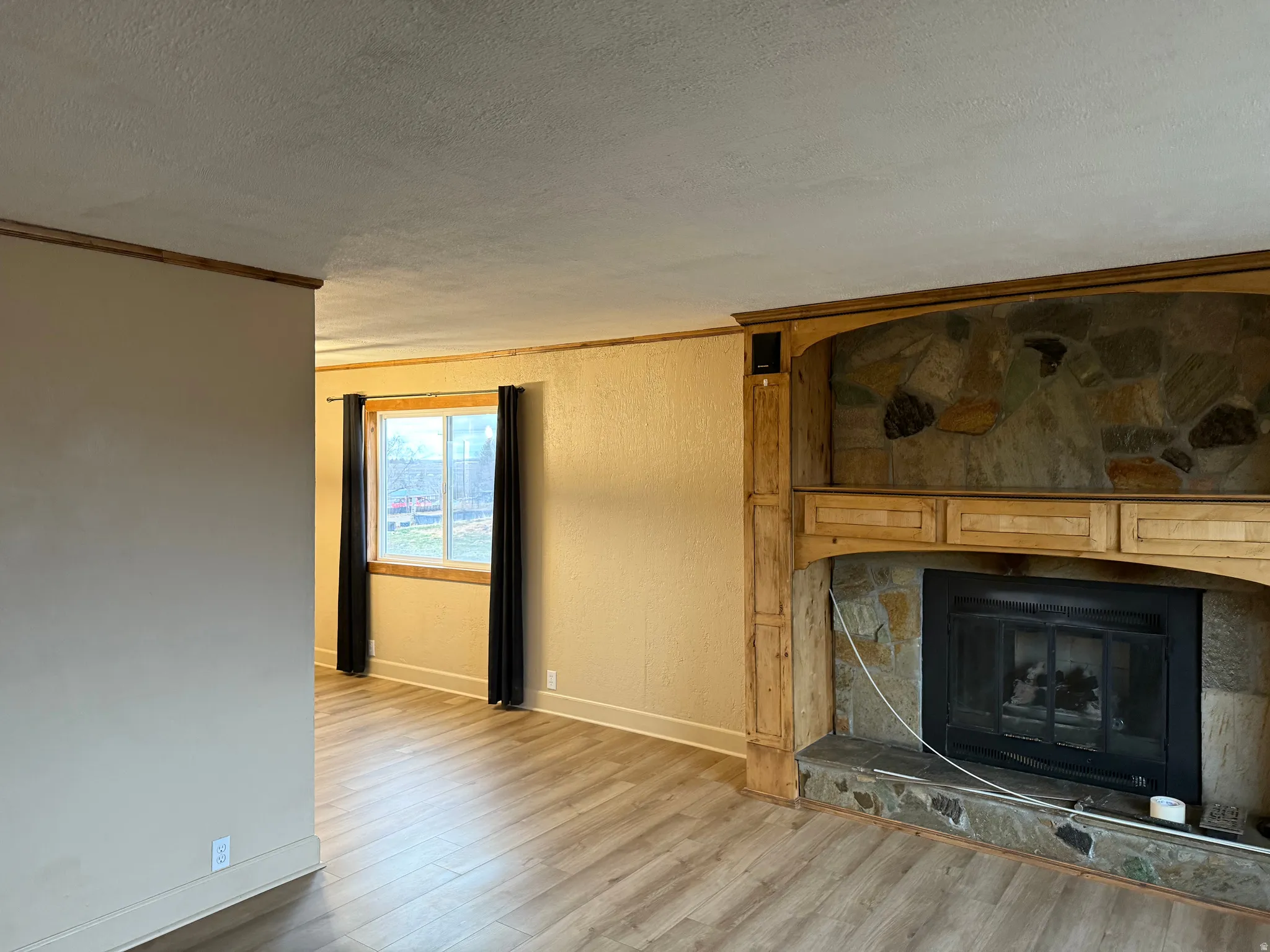 Stone-faced fireplace with a wood mantel, gas insert, and stone hearth