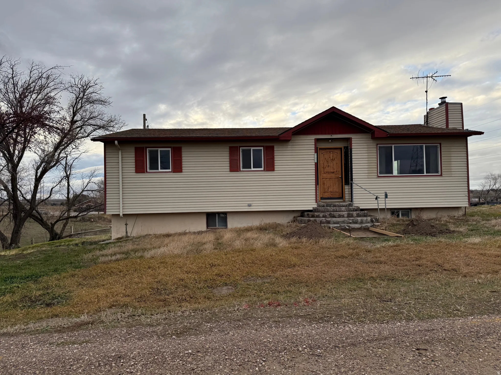 Siding exterior with red trim accents, exposed aggregate steps, and a brown front door with glass inserts