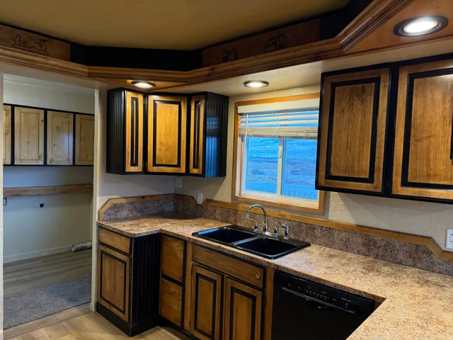 Kitchen featuring wood-finish cabinetry, laminate countertops, a black double-basin sink, and a black dishwasher