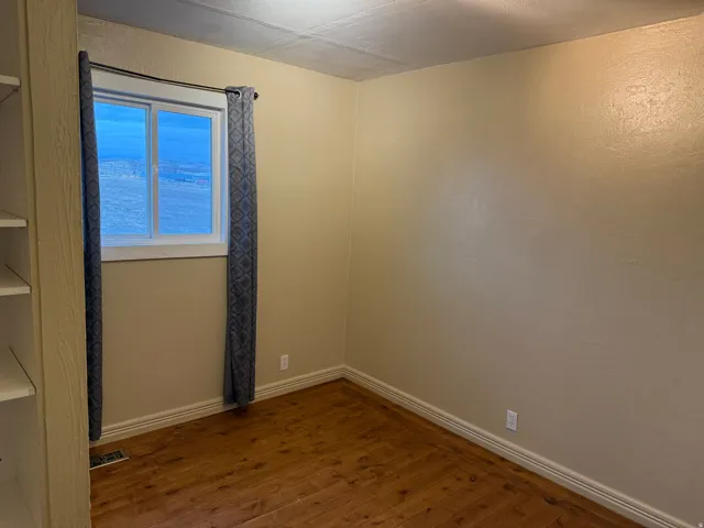 Wood-finish flooring with white baseboards and light-toned walls