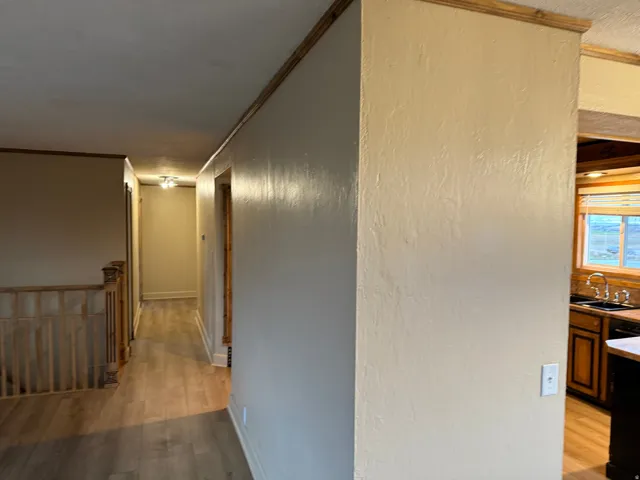 Wood-finish flooring throughout, light neutral wall tones, wood trim accents, and overhead lighting