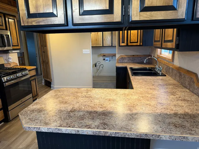 U-shaped kitchen counter with a double basin sink and stainless steel faucet, complemented by wood-finish cabinetry