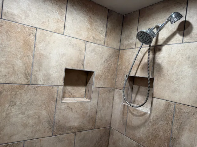 Tiled shower surround with two recessed niches and a handheld showerhead