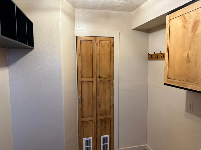 Wood-finish bifold door, built-in wooden cabinet, and coat hooks