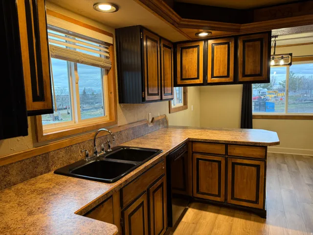 Kitchen featuring wood-finish cabinetry, a double basin sink, and ample countertop space