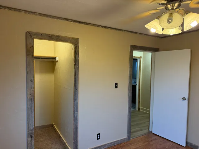 Neutral wall paint, wood-finish flooring, and a ceiling fan with integrated lighting