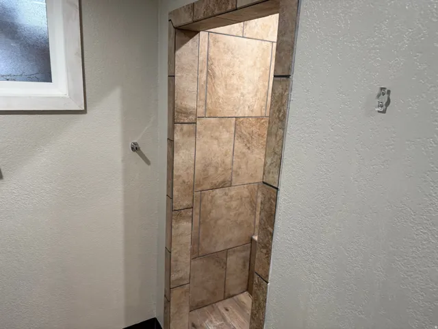 Tiled shower enclosure featuring varied tile sizes and an integrated bench