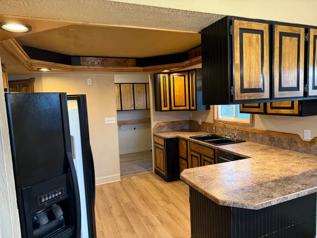 Kitchen featuring wood-finish flooring, two-tone cabinetry, U-shaped countertops, a double basin sink, and recessed lighting