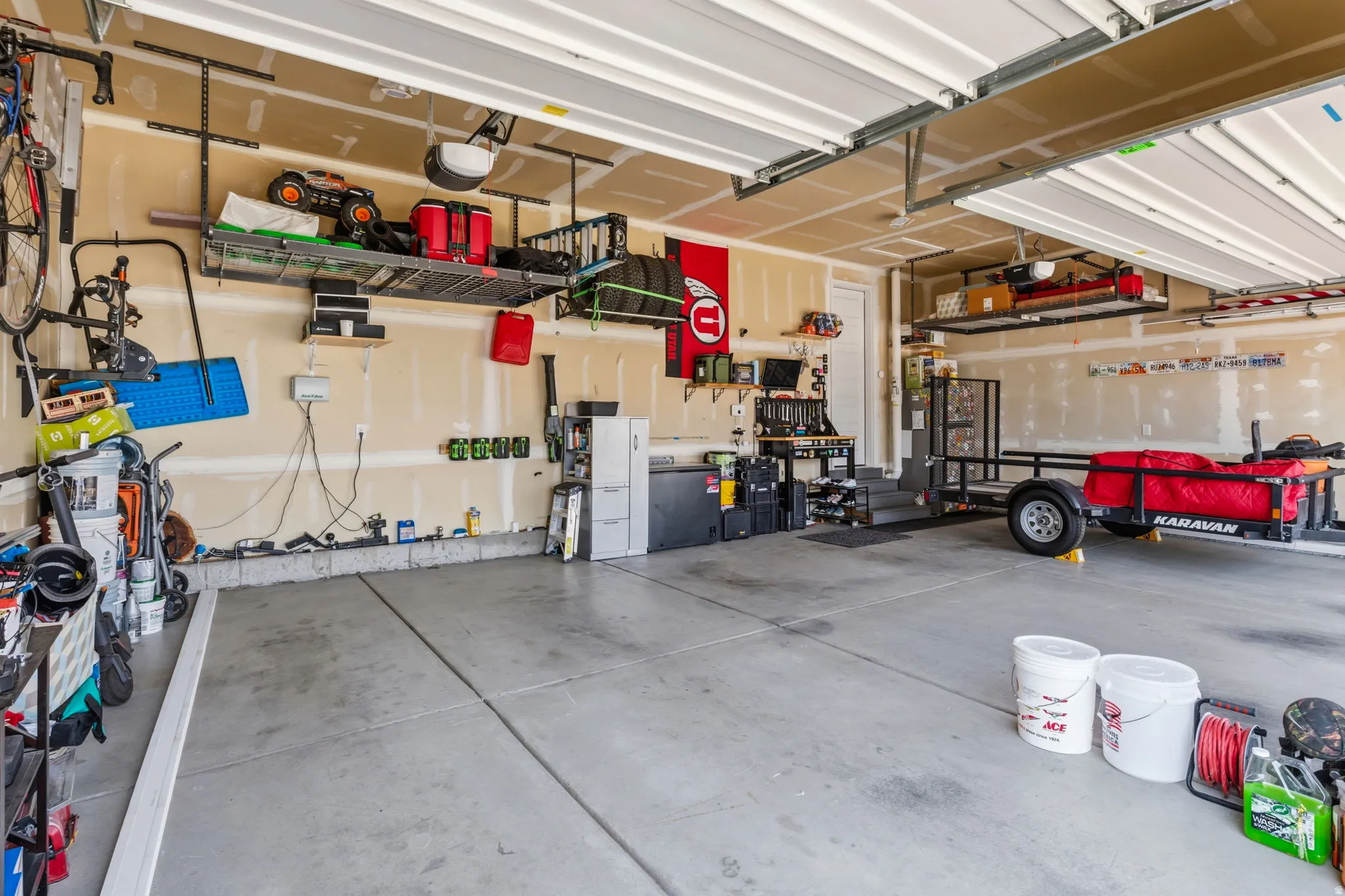 Attached garage with concrete flooring, overhead storage racks, and wall-mounted shelving