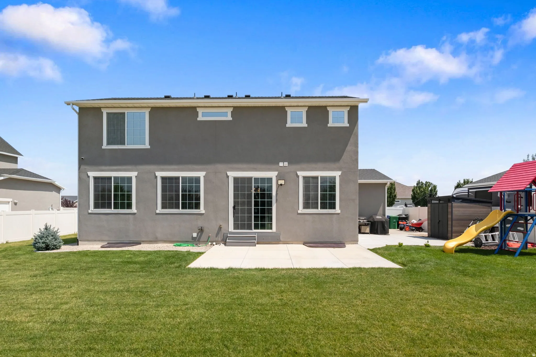 Expansive backyard with a manicured lawn, concrete patio, and a privacy fence